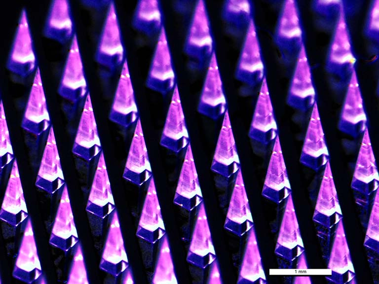 rows of pyramid-shaped microneedles, glowing magenta